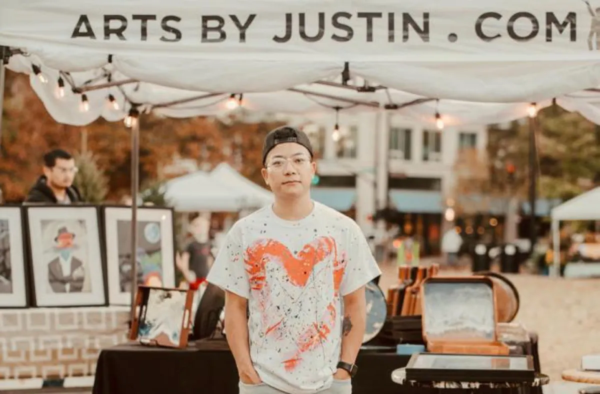 Justin standing together with his work in the background