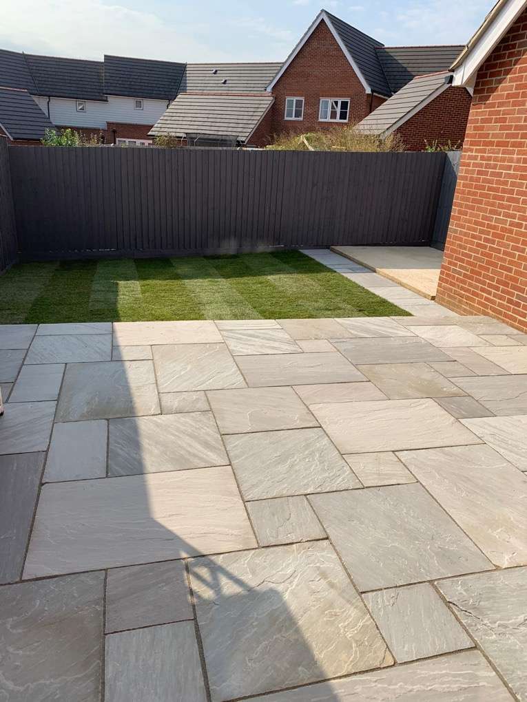 Sandstone patio installation at new build property with fresh turf and fencing — ACE Paving