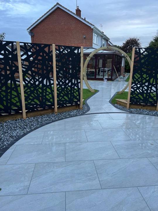 Circular porcelain patio with moon gate arch and decorative screens in Berkhamsted