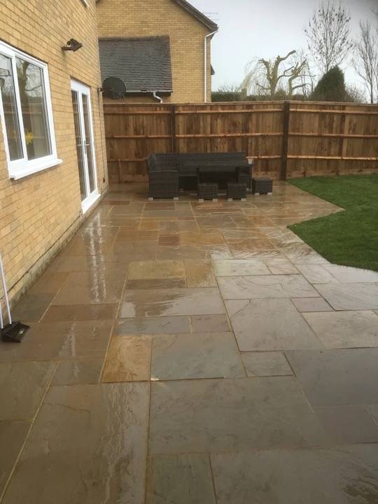 Completed sandstone patio with rattan furniture and new fencing in Tring