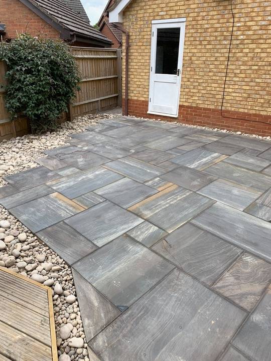 Grey and blue sandstone patio with pebble borders installed by ACE Paving