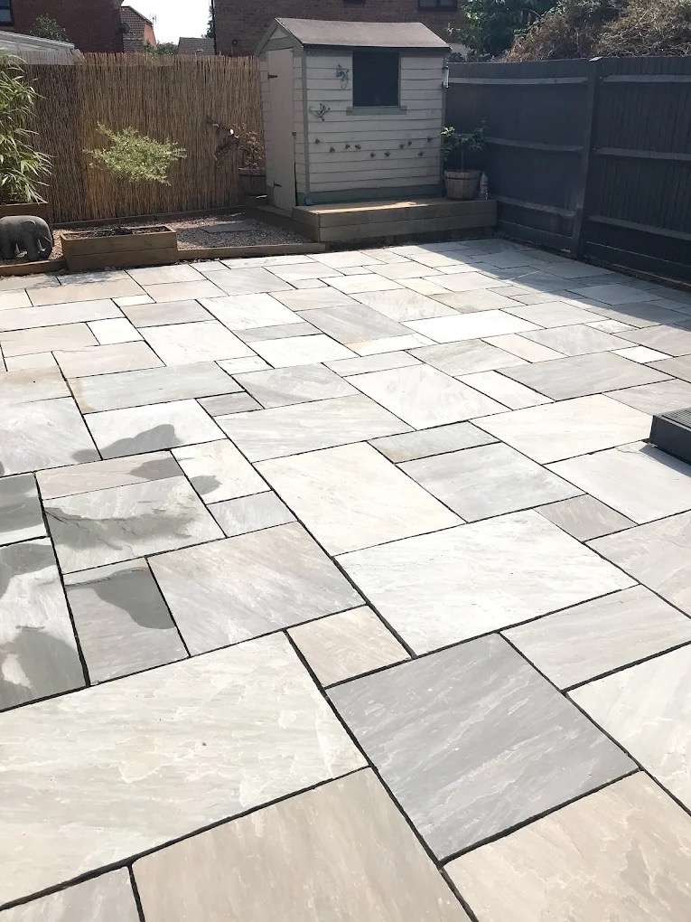 Completed sandstone patio with sleeper borders, shed, and garden — ACE Paving