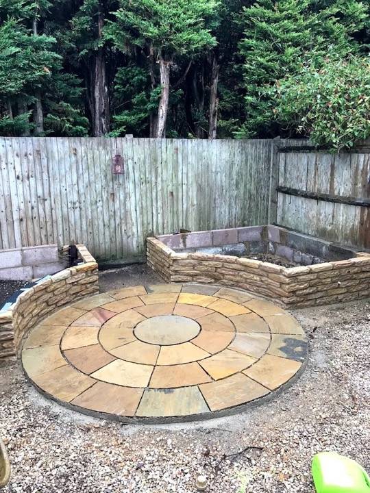 Circular sandstone feature with stone raised beds in rear garden