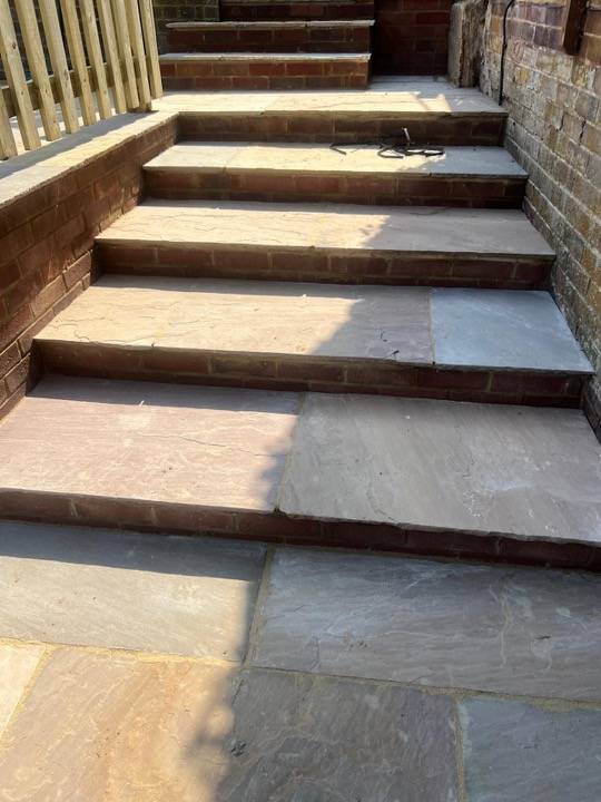 Finished sandstone steps with warm tones and brick retaining wall
