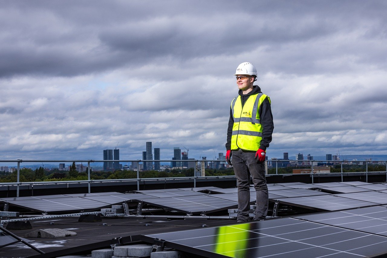 Licensed solar engineer standing on a rooftop system with city skyline in background