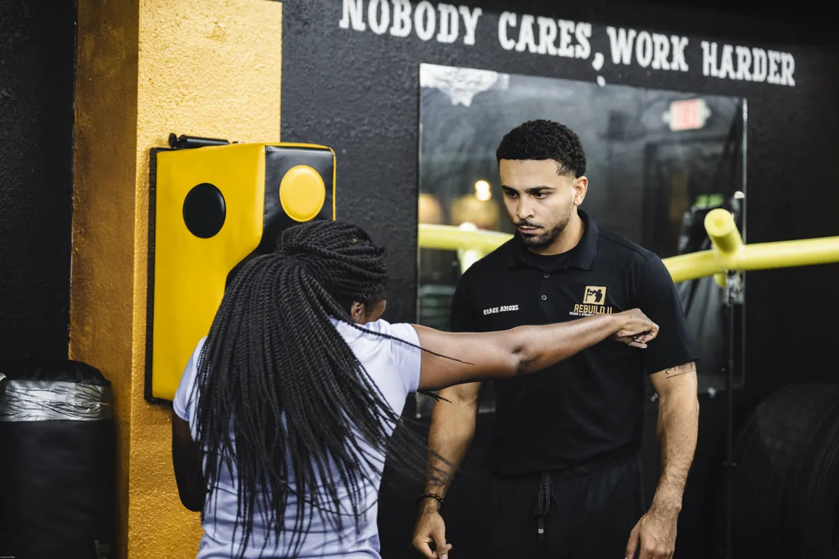 Coach Angel guiding a client’s punch at Rebuild U