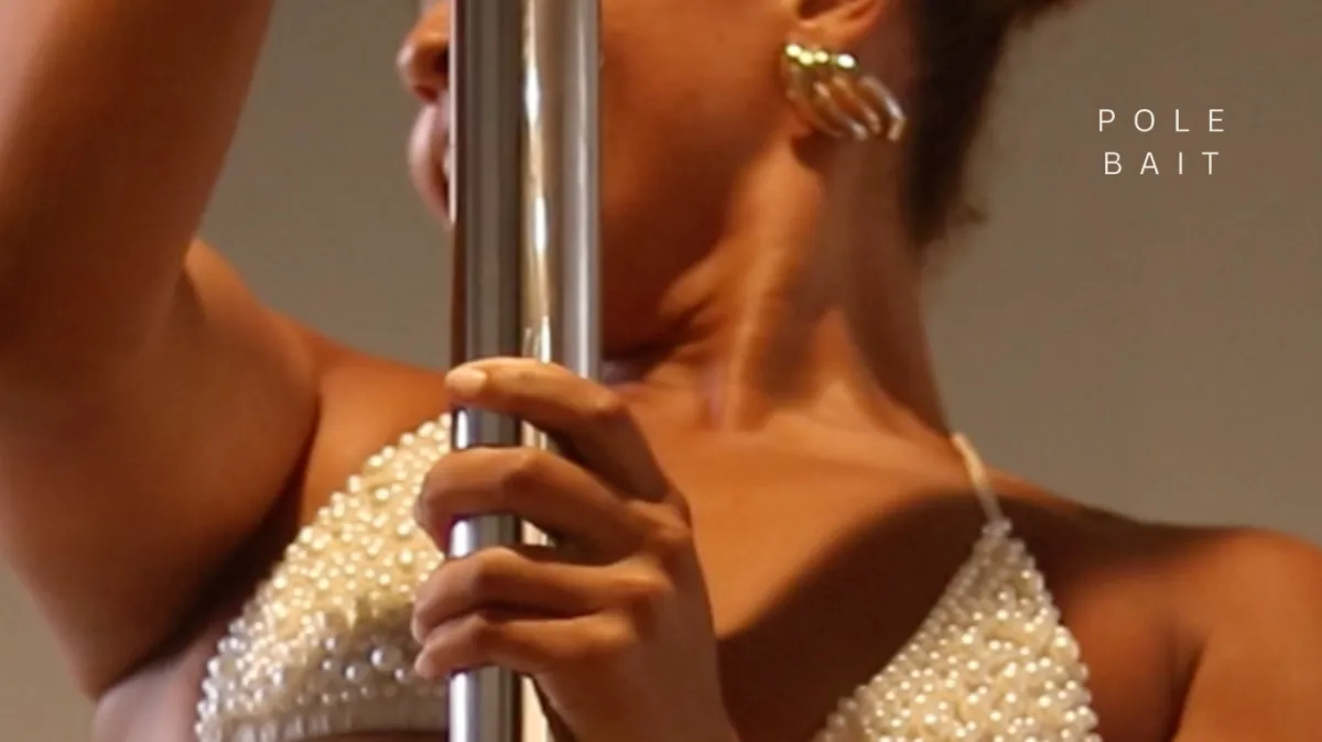 Woman in pearl top holding a pole at PoleBait studio