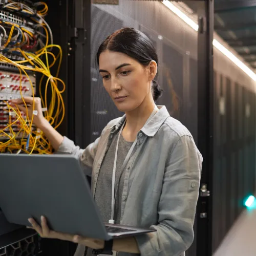 woman connected to a switch on laptop in a datacenter