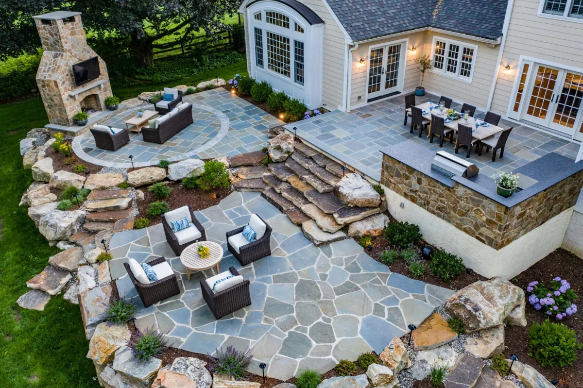fields by duran: Contemporary backyard with tall privacy hedges, square shrub planters, stone walkway, green lawn, and a modern house with vine-covered walls.