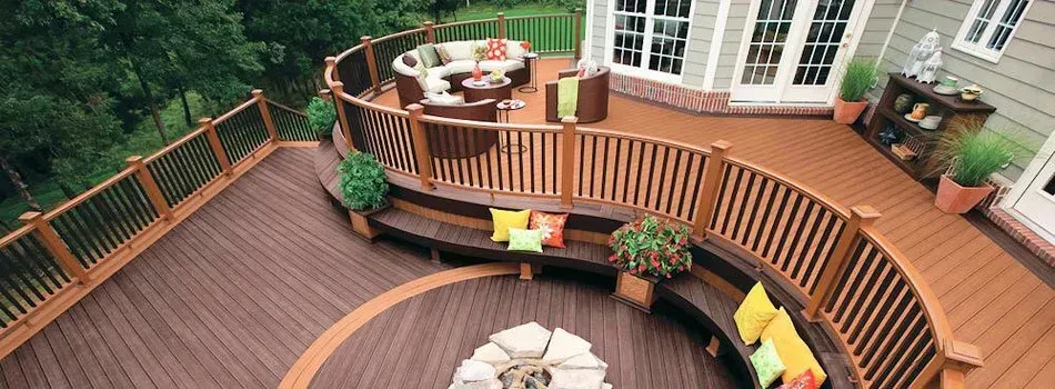 fields by duran: Spacious curved wooden deck with built-in seating, colorful cushions, and outdoor furniture in a backyard.