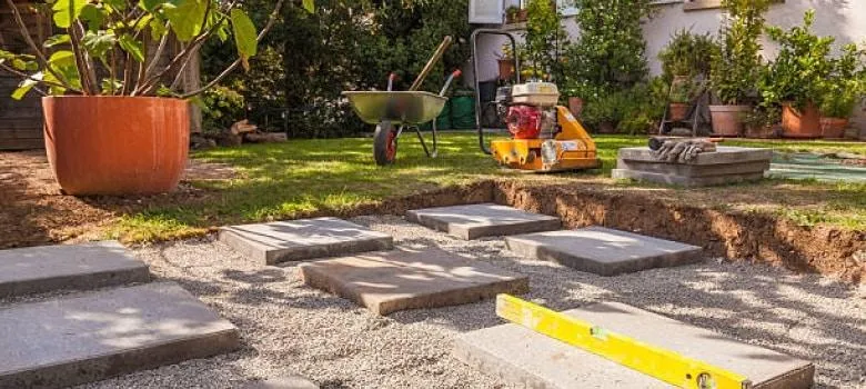 fields by duran: Garden landscaping in progress with stepping stones being installed on a gravel base in a backyard.