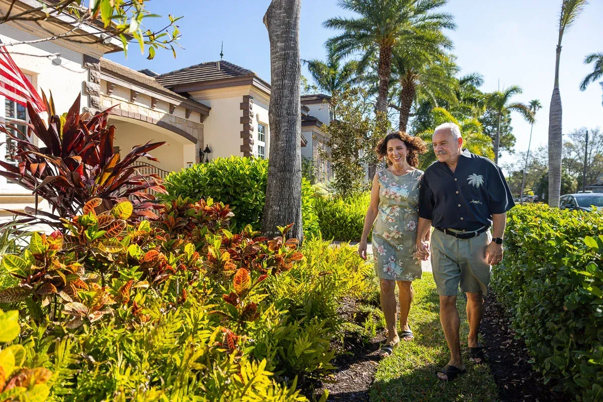 fields by duran: Happy couple walking hand in hand through a beautifully landscaped tropical garden with palm trees.