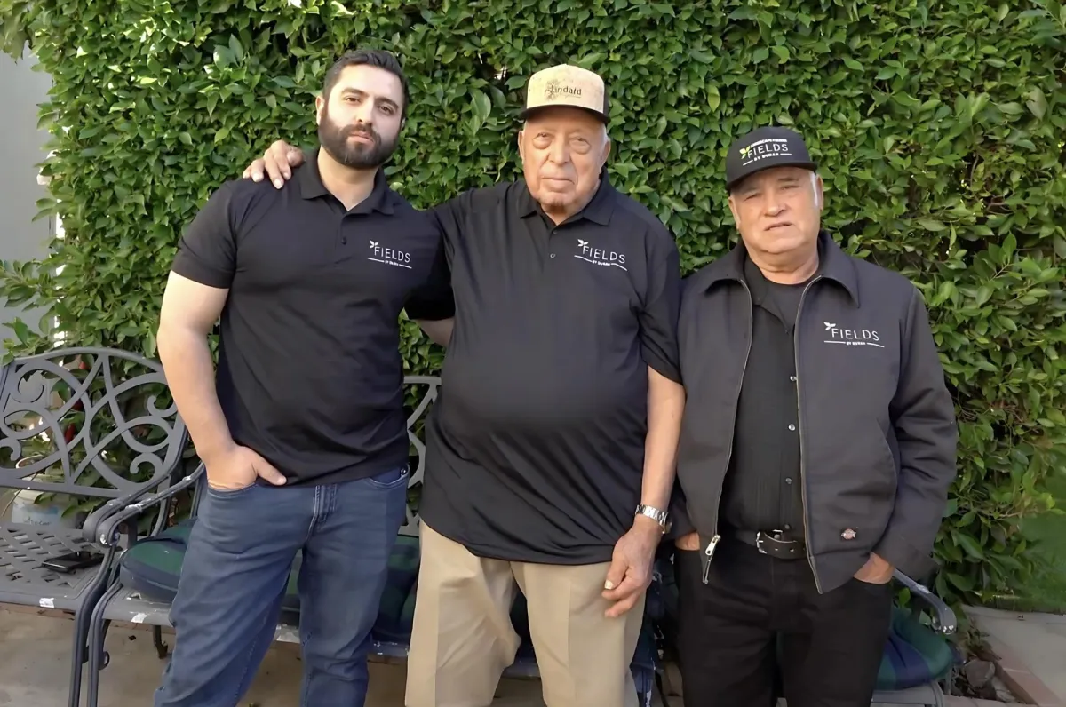 fields by duran: Three men from Fields by Duran landscaping team posing together outdoors in branded uniforms.
