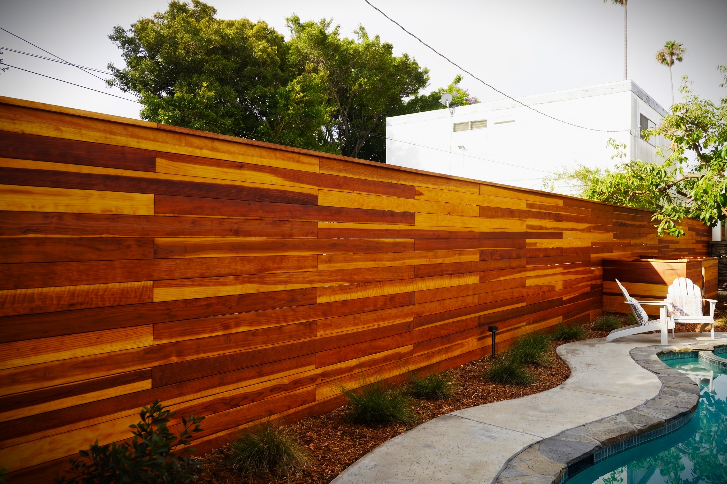 fields by duran: Modern wooden garden gate opening to a stone pathway surrounded by lush tropical plants.