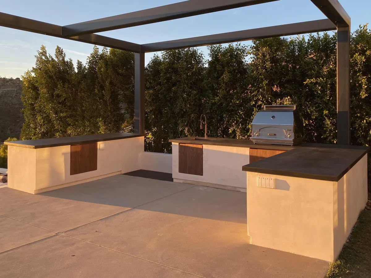 fields by duran: Luxury outdoor kitchen with stone countertops, stainless steel appliances, bar seating, and a view of the backyard and playhouse.