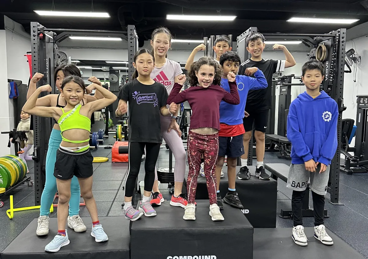 Group of kids smiling on top of three pedestals, they are all winners