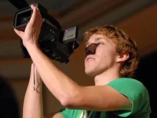 Adam Morrison, in a green shirt, filming at a concert during his first or second year of college in 2006.