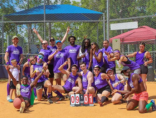 A vibrant photo of the HotMess Kickball team captained by Adam. The team, showcasing enthusiasm and leadership, enjoys a moment of fun on the field.