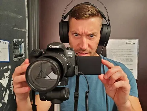 Adam Morrison behind a Canon camera recording with headphones on