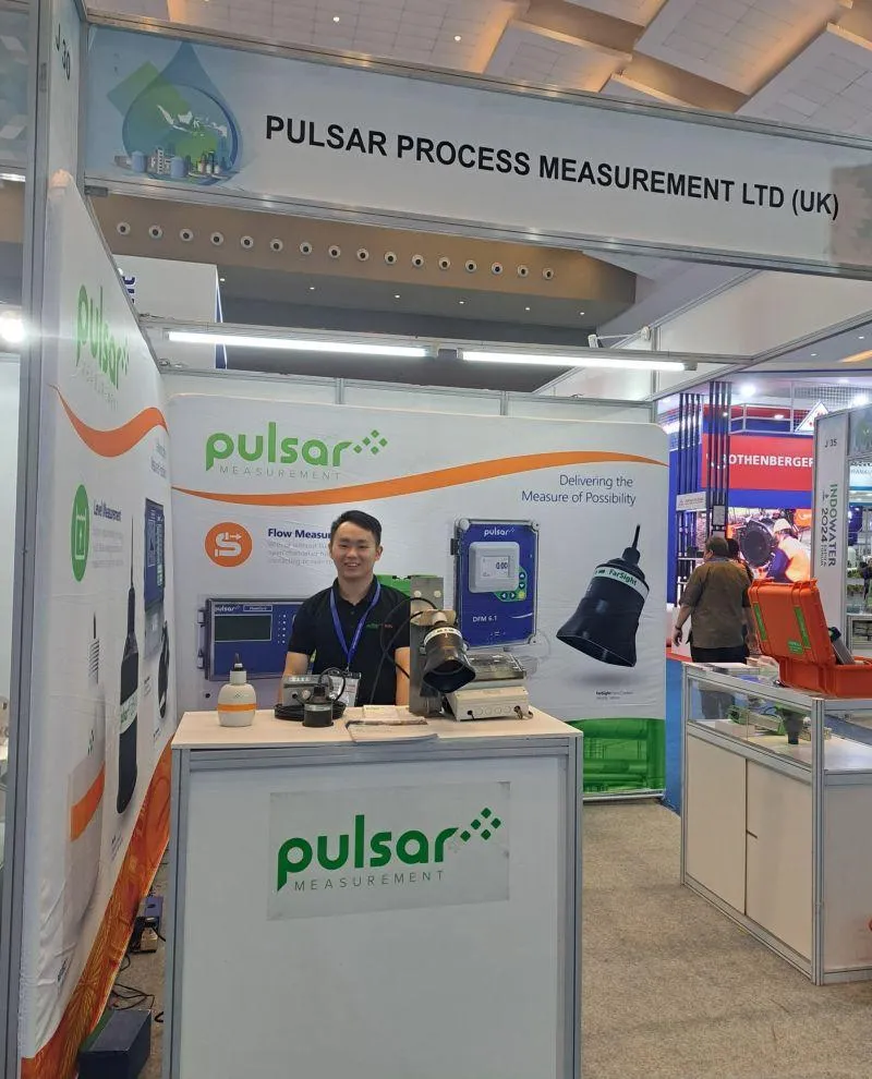 Various Pulsar Measurement products on display at a trade show booth, including flow meters and level sensors.