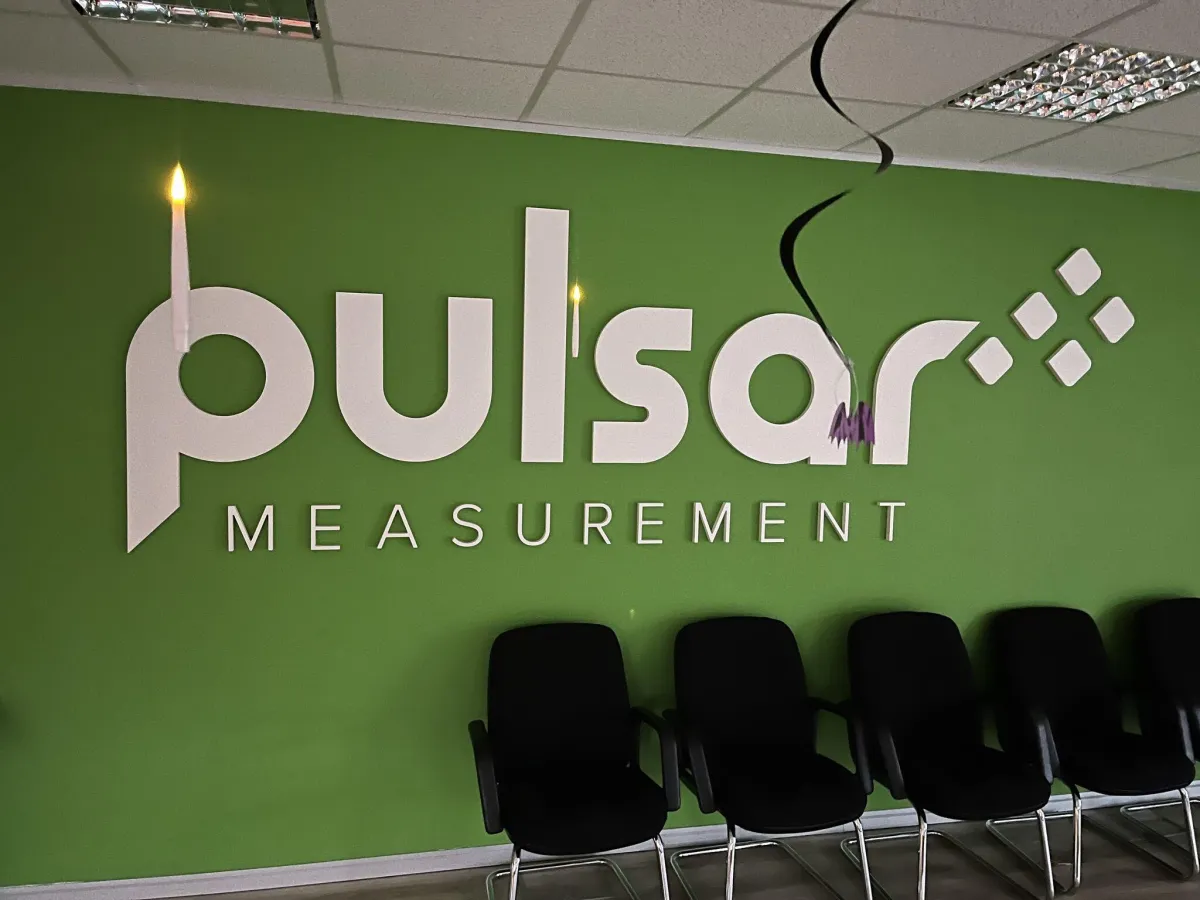 The Pulsar Measurement logo on a decorated office wall during Halloween, with spooky candles and decorations.