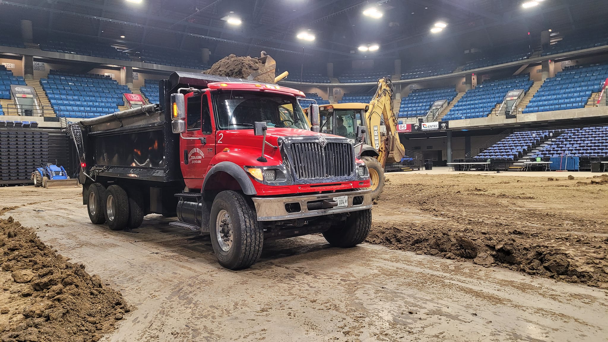 Grunge-styled dump truck backing into a rock pit with dust and debris