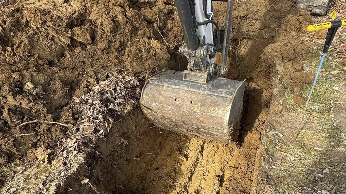 Septic vacuum truck hose connected to a tank in a muddy yard with grunge overlay