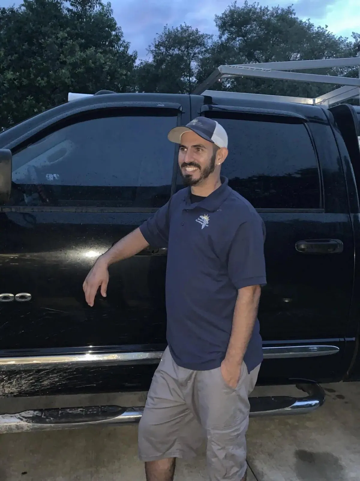 Business owner standing next to his truck wearing a shirt with the company logo