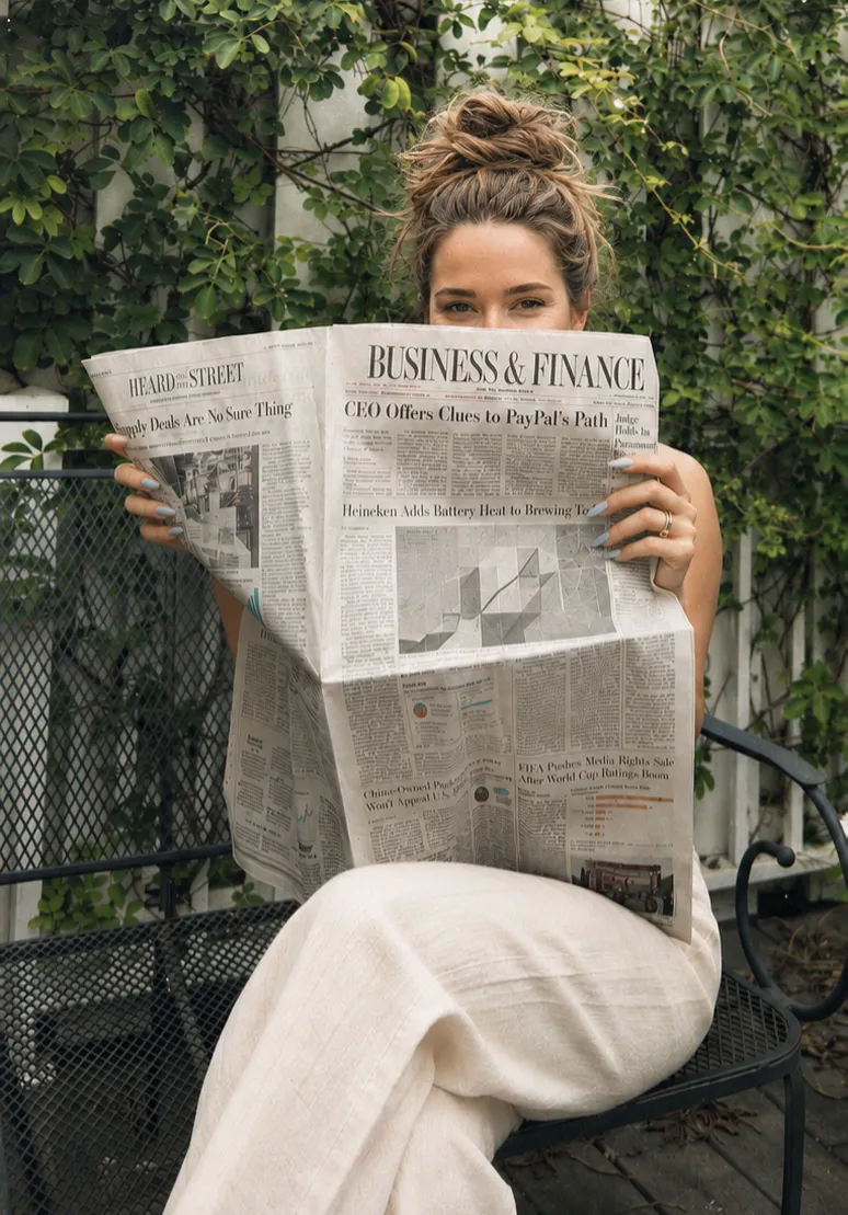 Woman sitting outside reading the newspaper