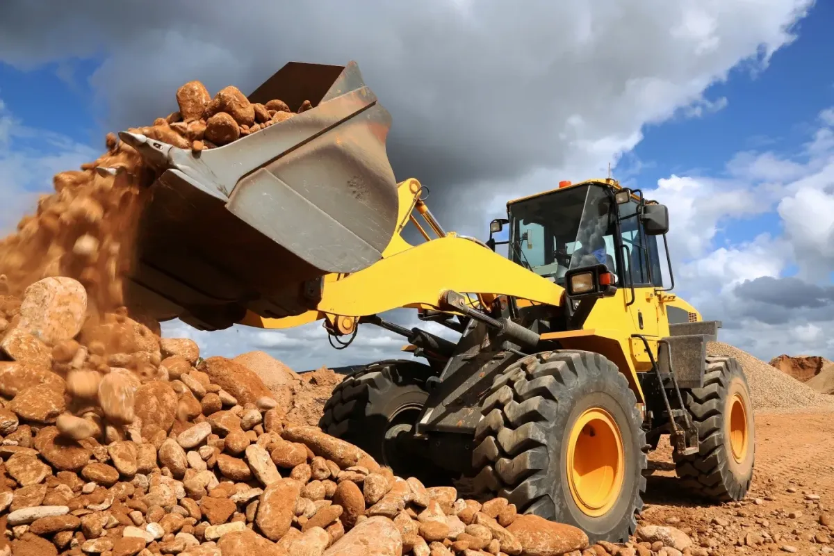 Wheel loader moving rocks at a construction site, representing heavy machinery training and machinery tickets