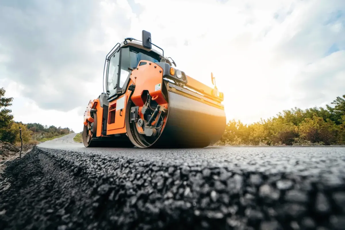 Road roller compacting fresh asphalt during road construction work