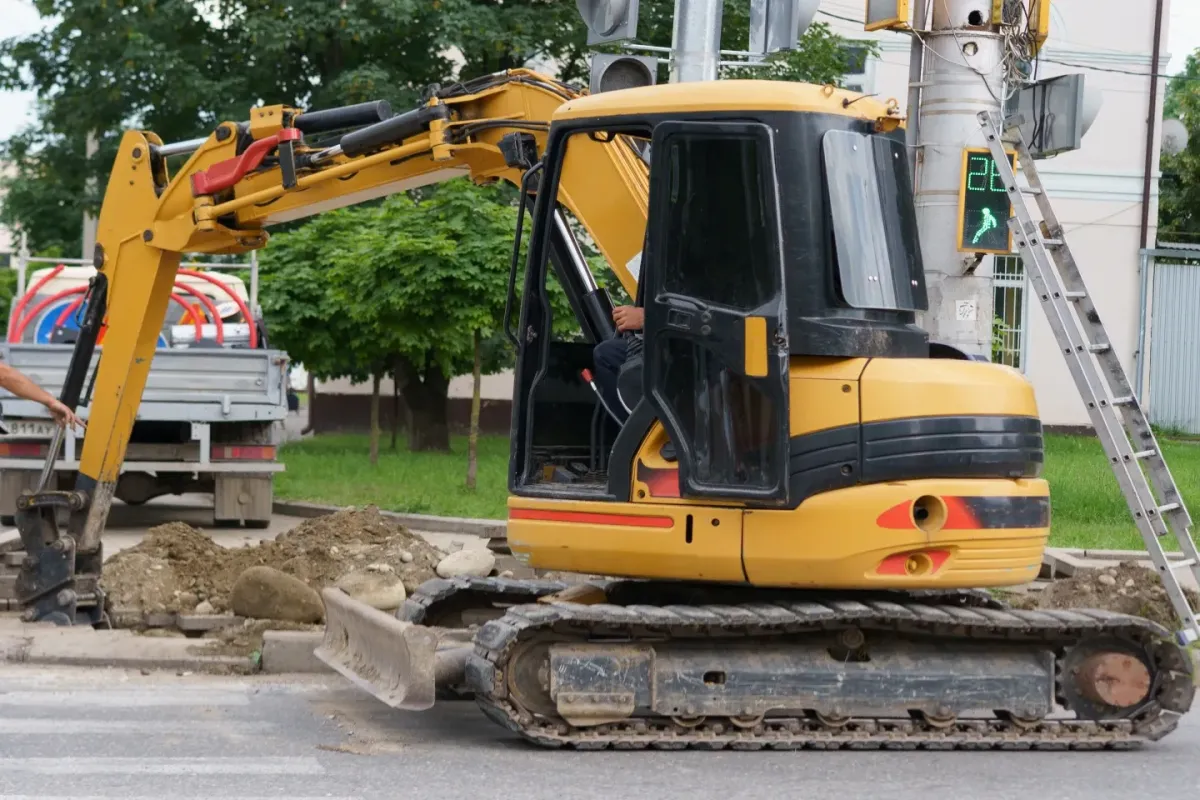 Mini excavator digging beside a roadside work area during urban construction and utility work