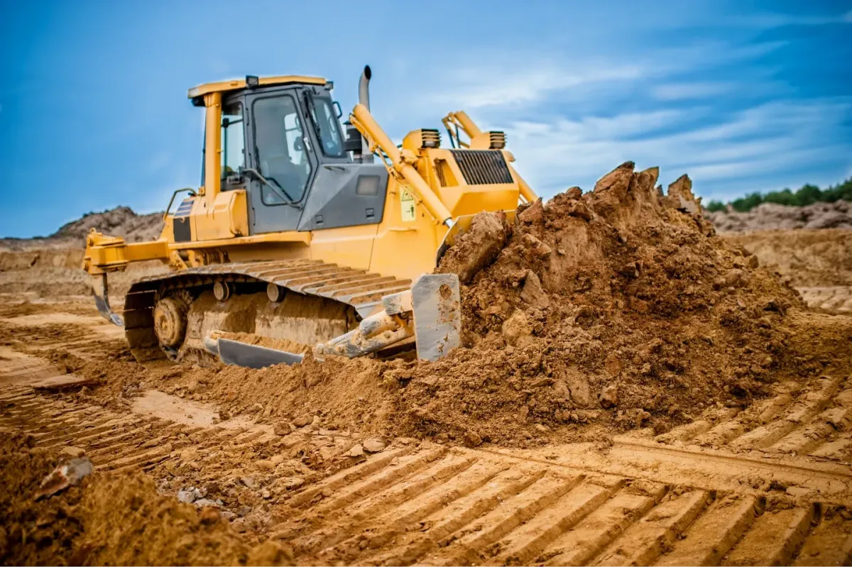 Bulldozer pushing a mound of soil across a dirt construction and earthmoving site