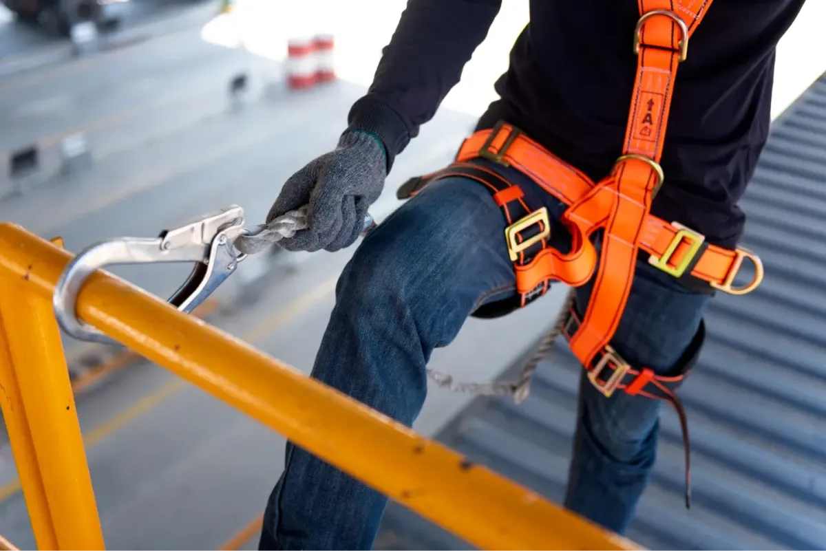 Worker wearing a safety harness and clipping onto a safety line while entering and working in a confined space