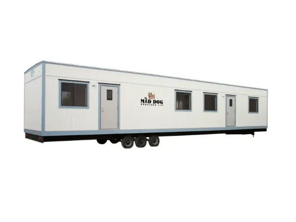A long, white mobile office trailer with blue trim and wheels, used for temporary offices by Maddog Services in Midland TX.