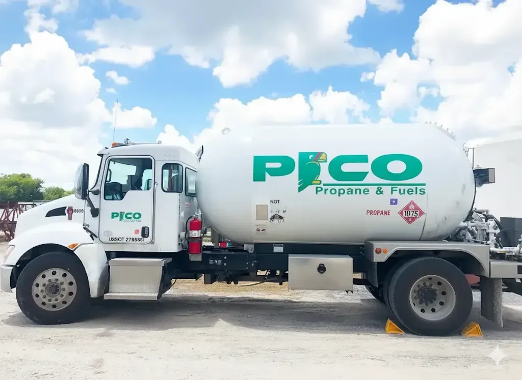 Propane & Fuels delivery truck with a white tank and green logo under a blue sky with white clouds.