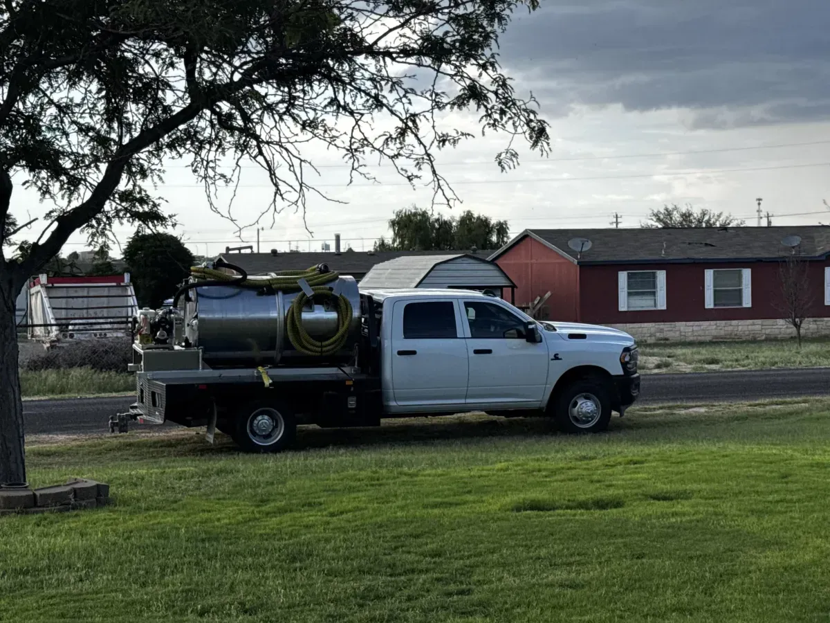 White Big Spring TX Maddog Services septic pump truck with a vacuum tank on a flatbed.