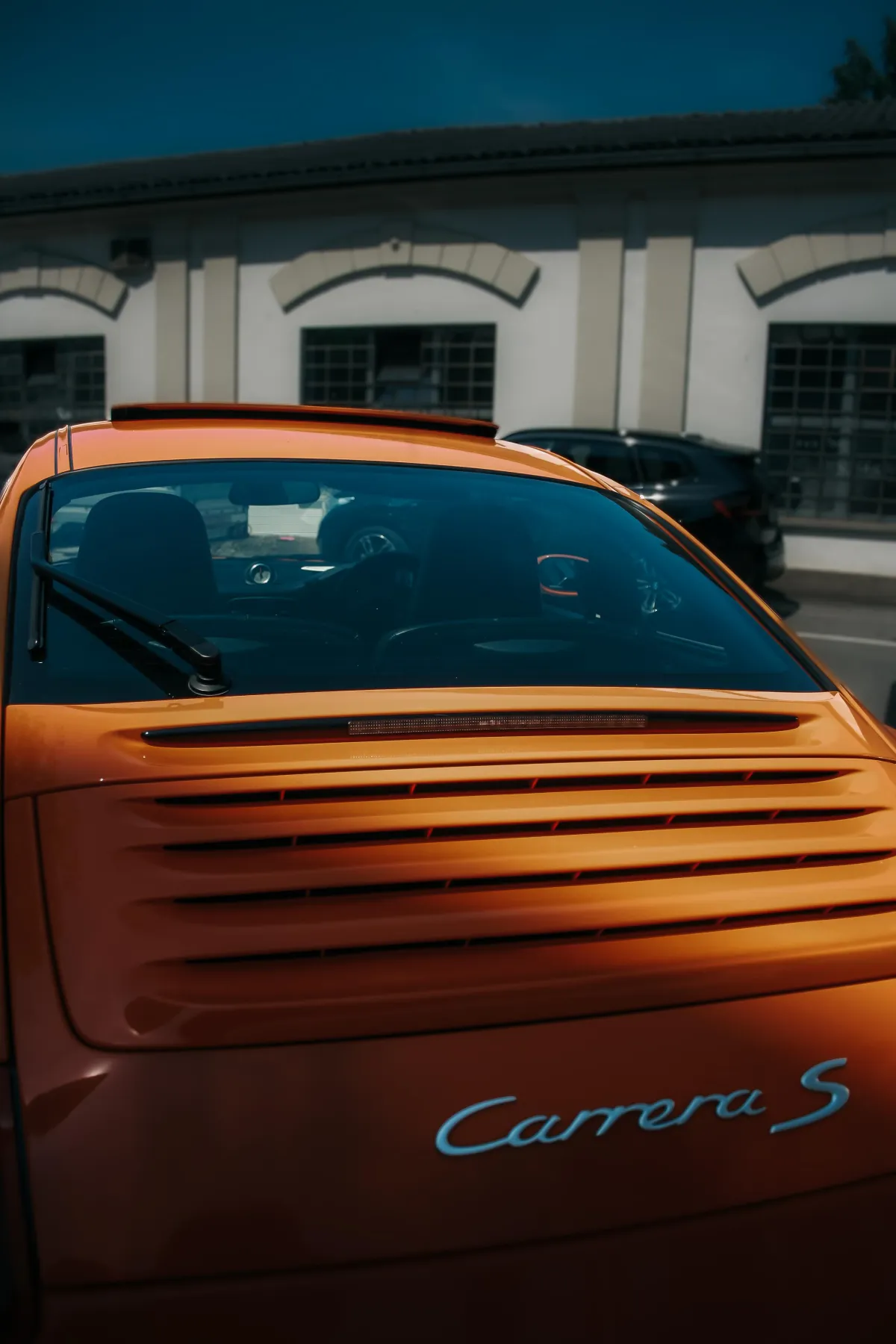 Bild von einem orangenen Porsche von hinten