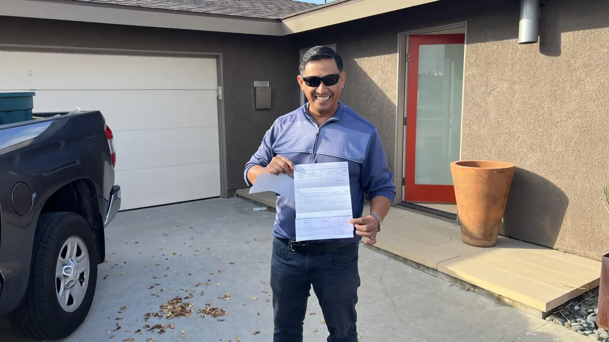 Happy home buyer receiving keys to their new house with a rebate check