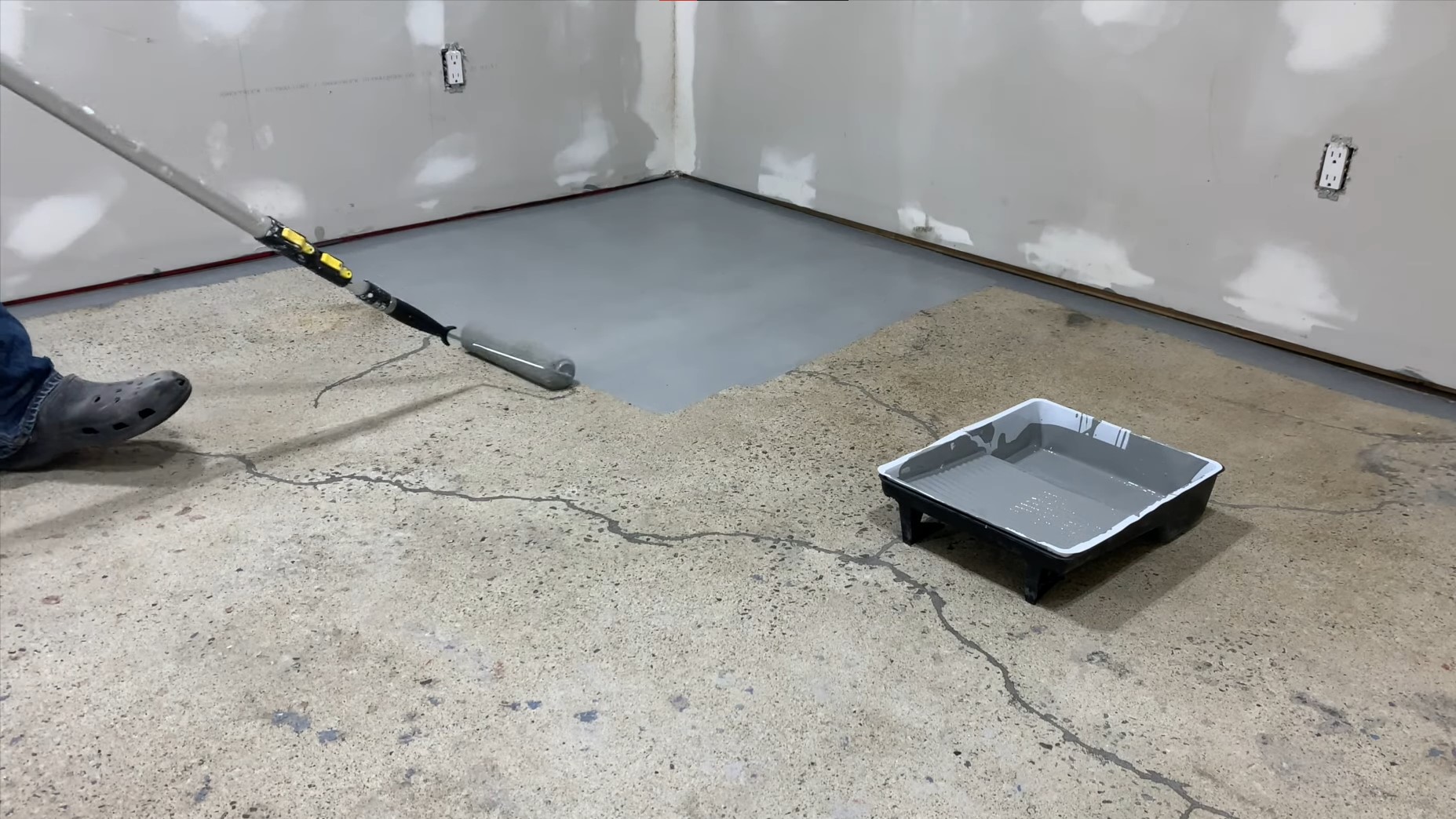 grey epoxy paint being spreaded on concrete garage floor