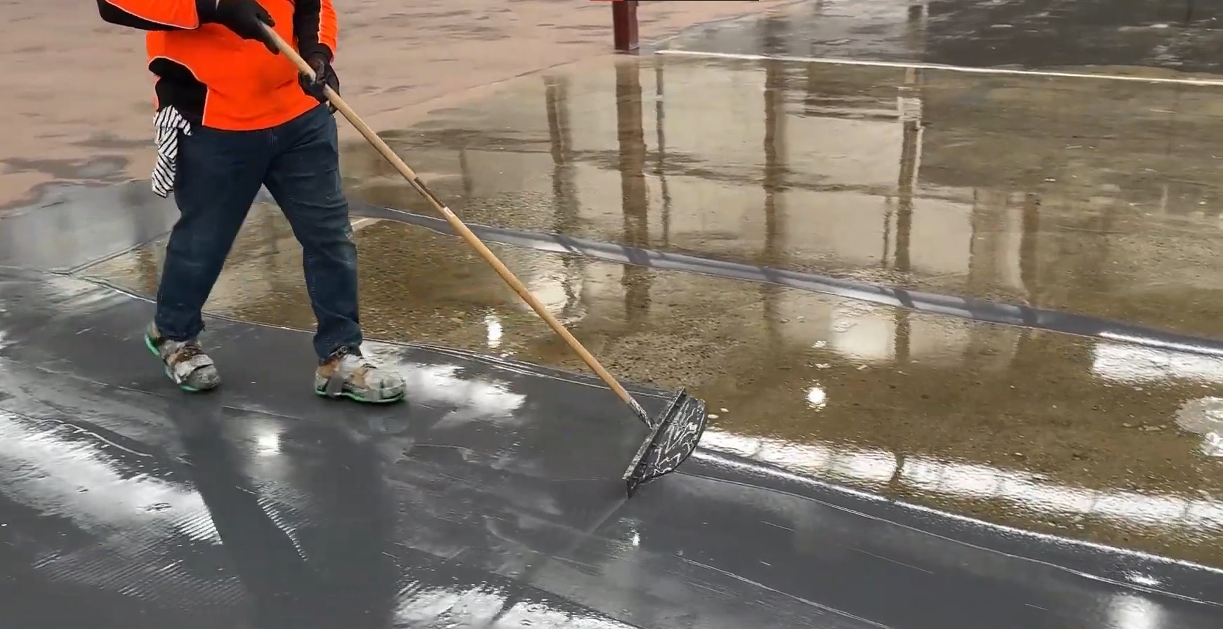 man using squeegee to apread epoxy grey basecoat to concrete floor