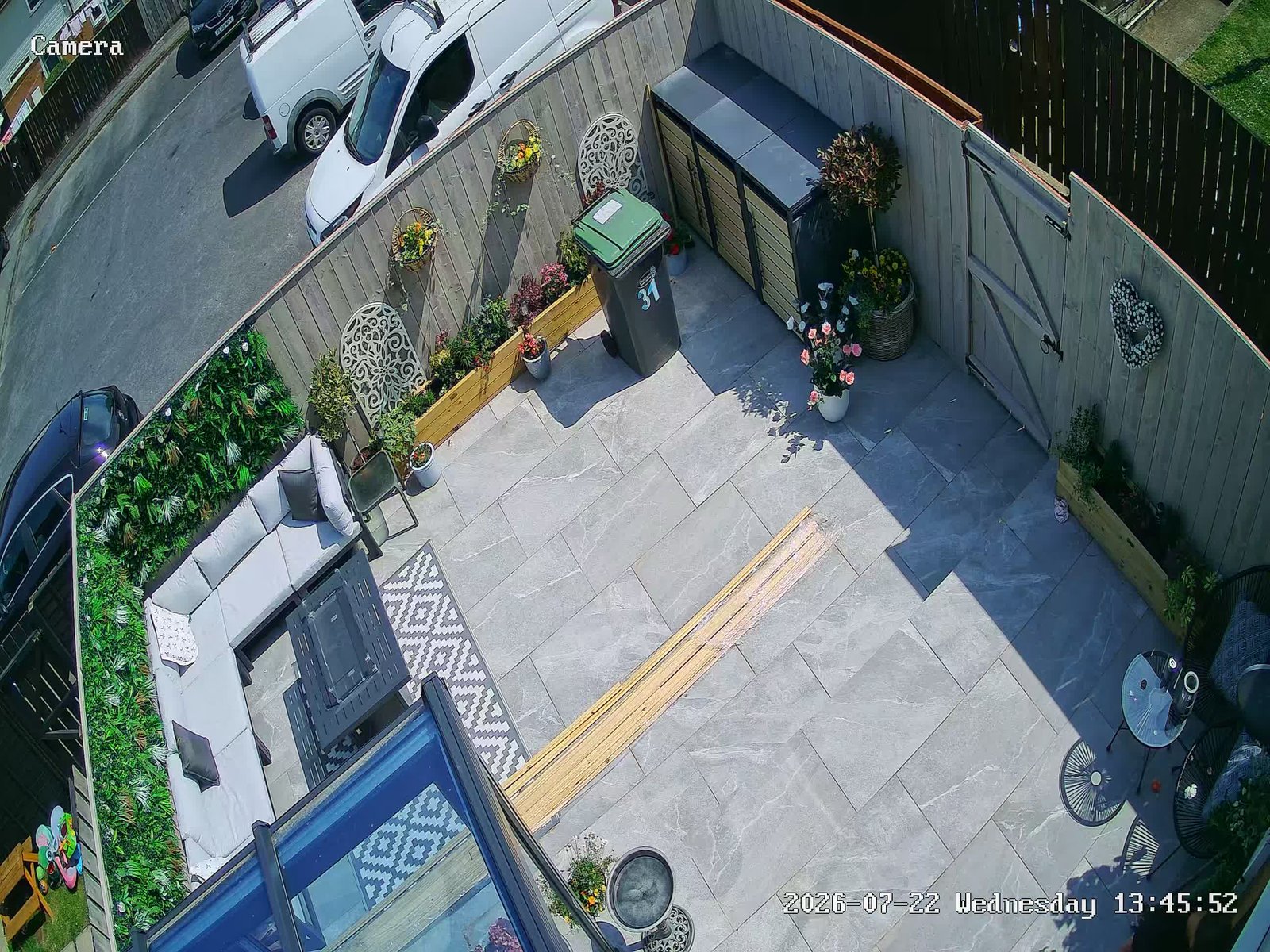 High-angle CCTV view of a paved patio, garden seating and side gate, installed by L&B Security