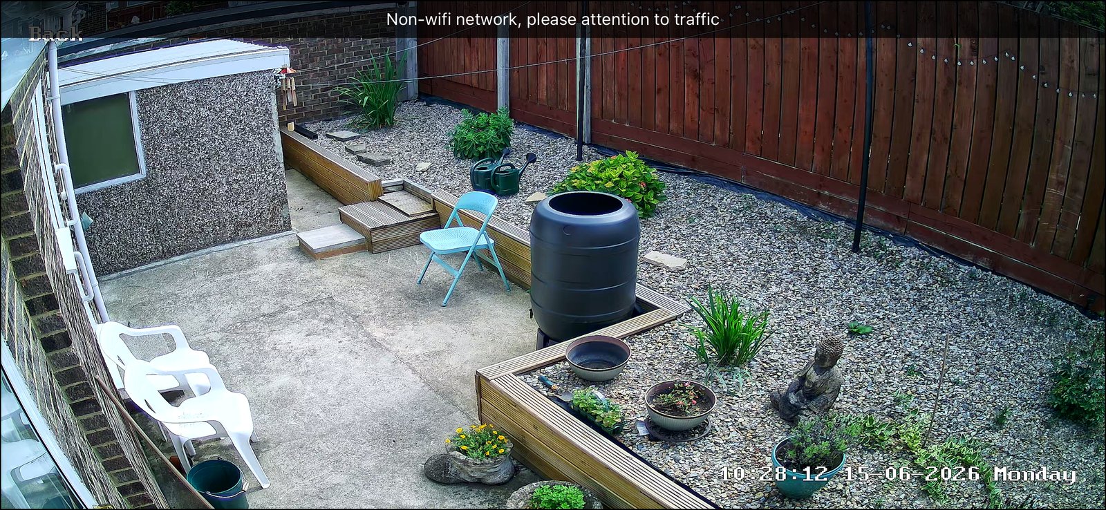 CCTV camera view of a gravel back garden with patio and planters, installed by L&B Security