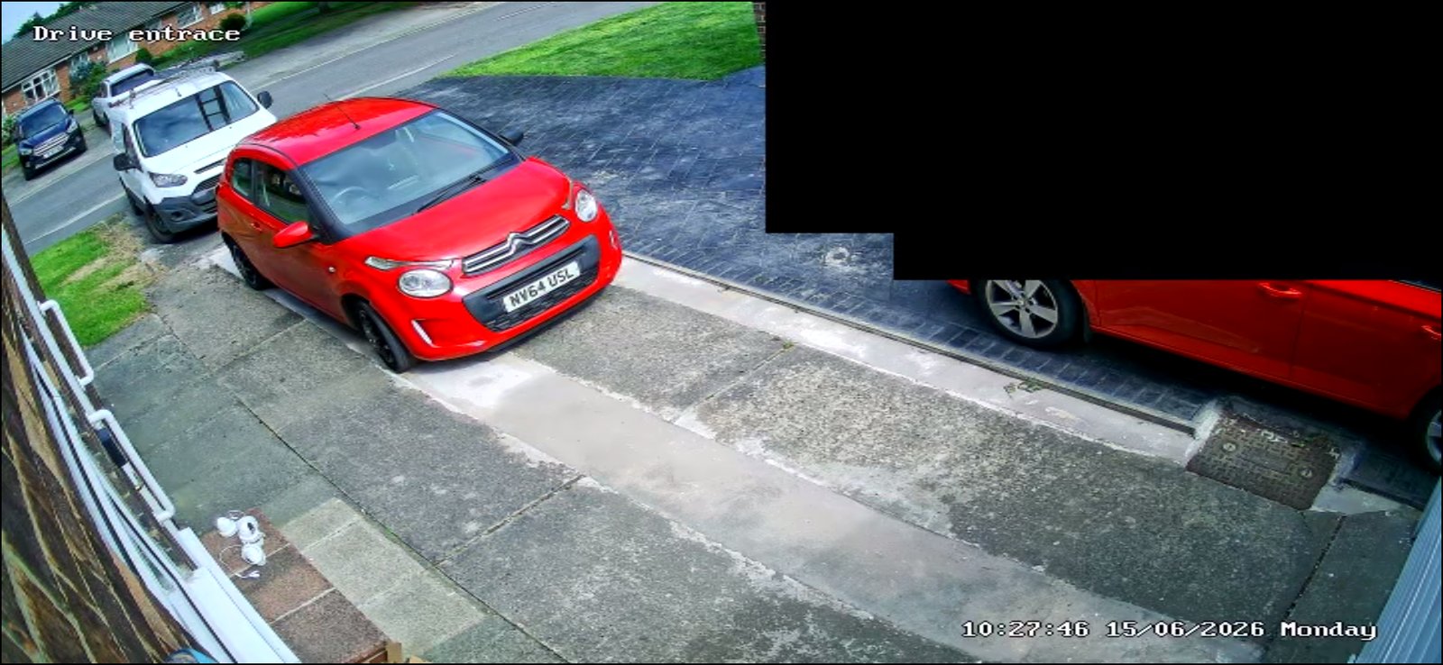 CCTV camera view of a driveway entrance with a red car parked, installed by L&B Security
