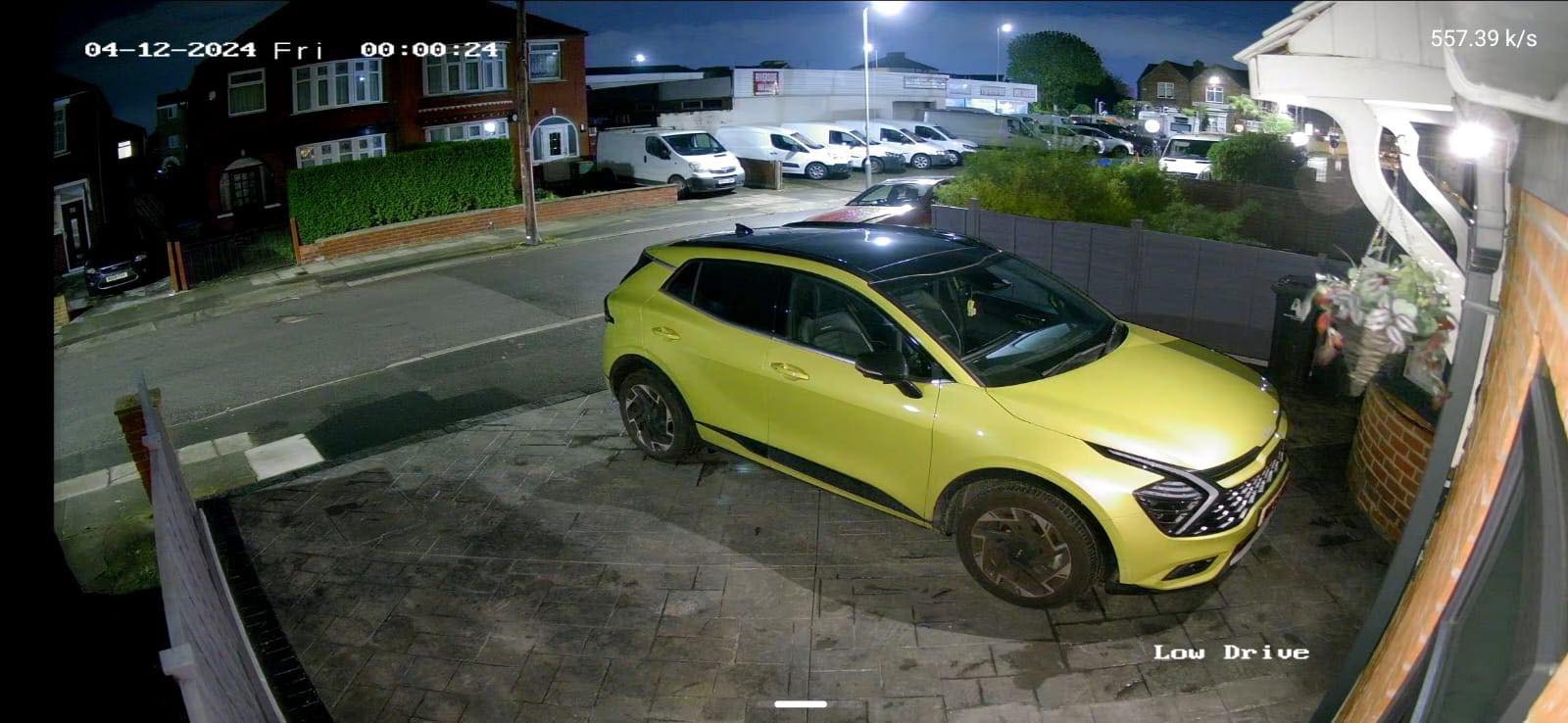 Night-time colour CCTV view of a driveway with a parked yellow car, installed by L&B Security