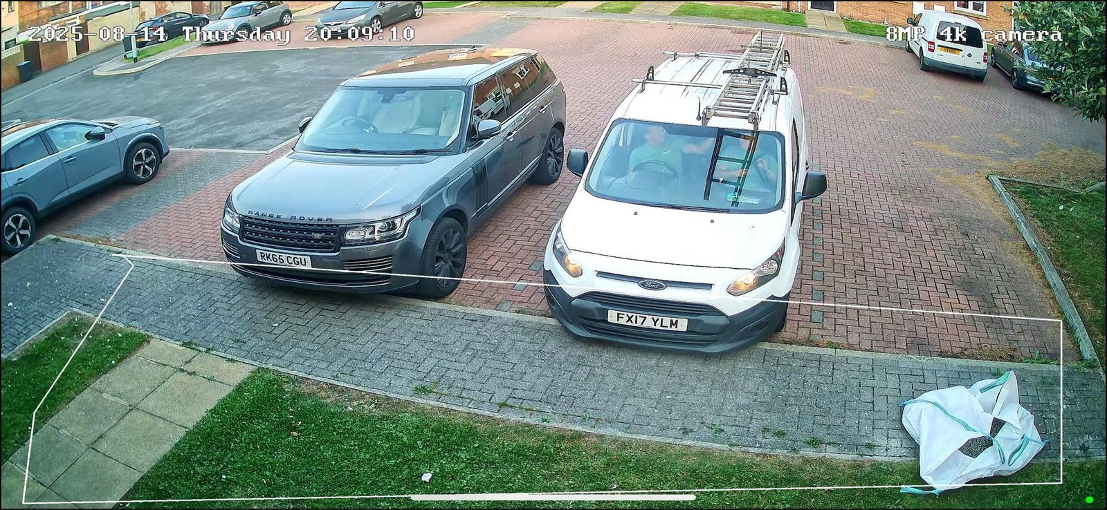 CCTV camera covering a block-paved parking area with a car and work van, installed by L&B Security