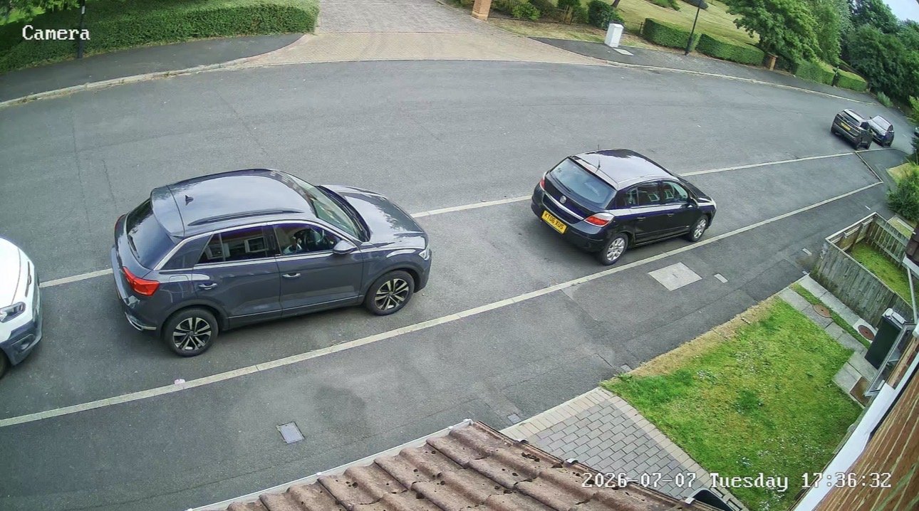 Wide CCTV camera view of a road and grass verge with passing cars, installed by L&B Security