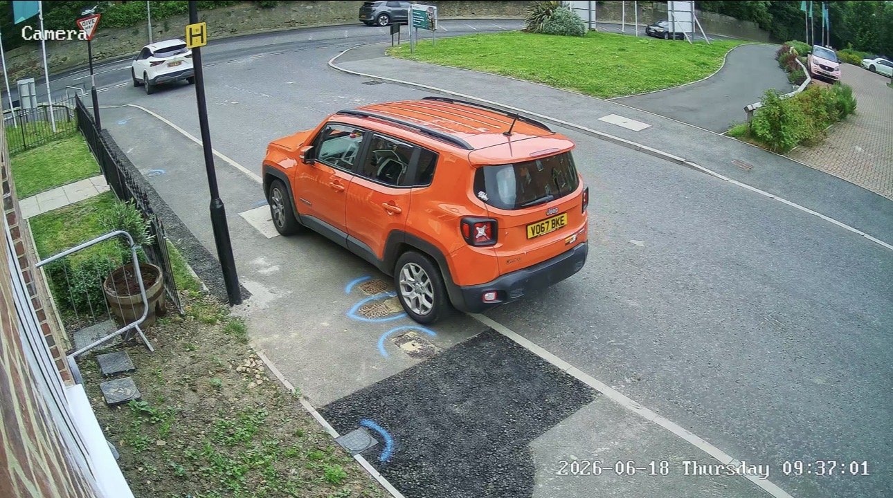 CCTV camera covering a pavement and roadside parking with an orange car, installed by L&B Security