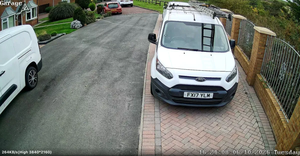 Spennymoor CCTV camera view of a block-paved driveway with a white van by a brick wall and railings