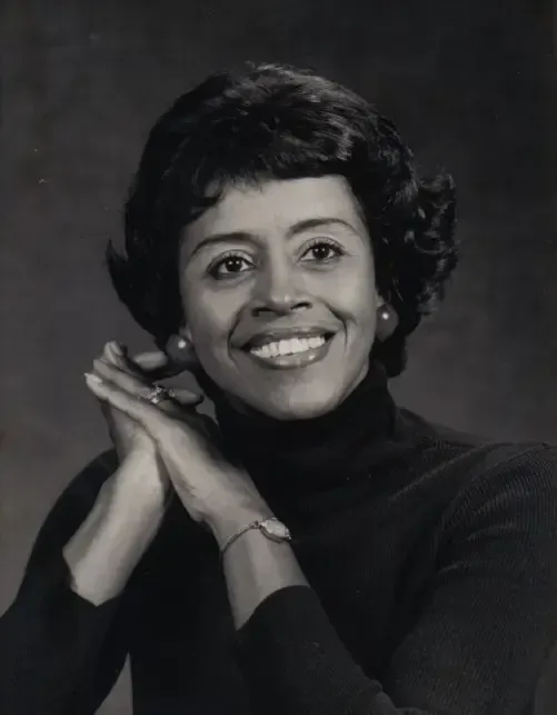 Portrait of a confident mid-40s Black female educator, three-quarter body with warm lighting.
